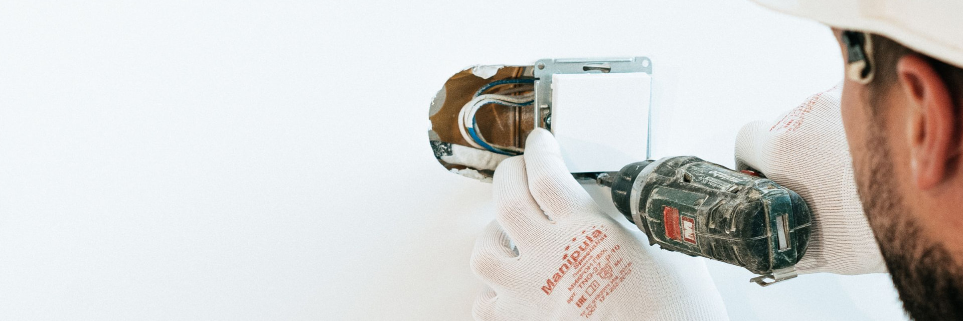 A tradesperson using a hammer drill on a wall fitting